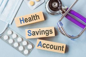 HSA, health savings account symbol. Wooden cubes with words 'HSA, health savings account'. Stethoscope. Wooden background. Medical and HSA, health savings account concept. Copy space.